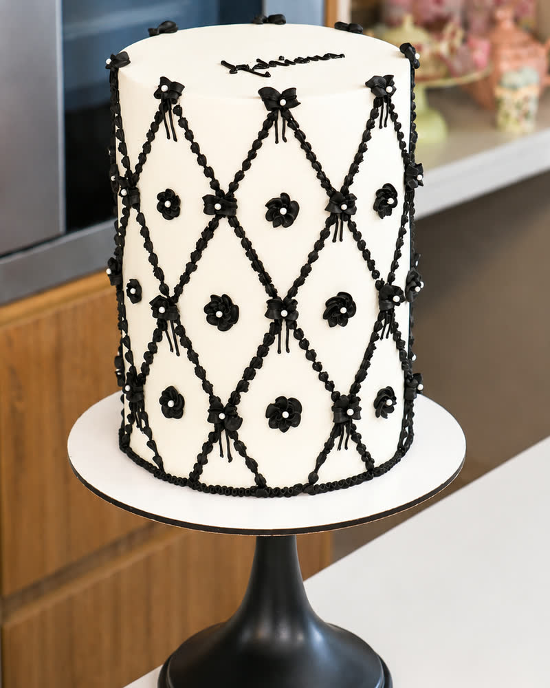 Pastel blanco con enrejado en rombos, moños y flores en negro